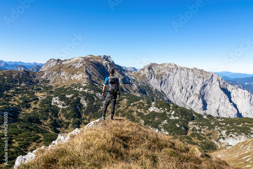 A man with a backpack enjoying panoramic view on the mountain peaks of the Hochschwab Region in Upper Styria, Austria. Sharp summits of Ebenstein and Hinterer Polster, Alps in Europe. Concept freedom photo