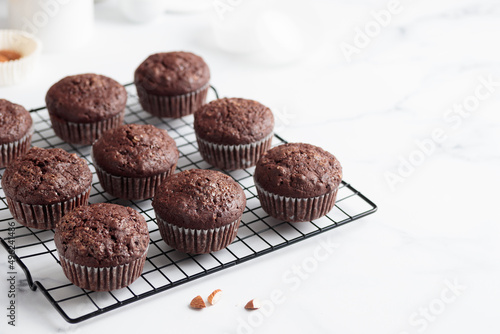 Freshly baked chocolate muffins on a grid on white table