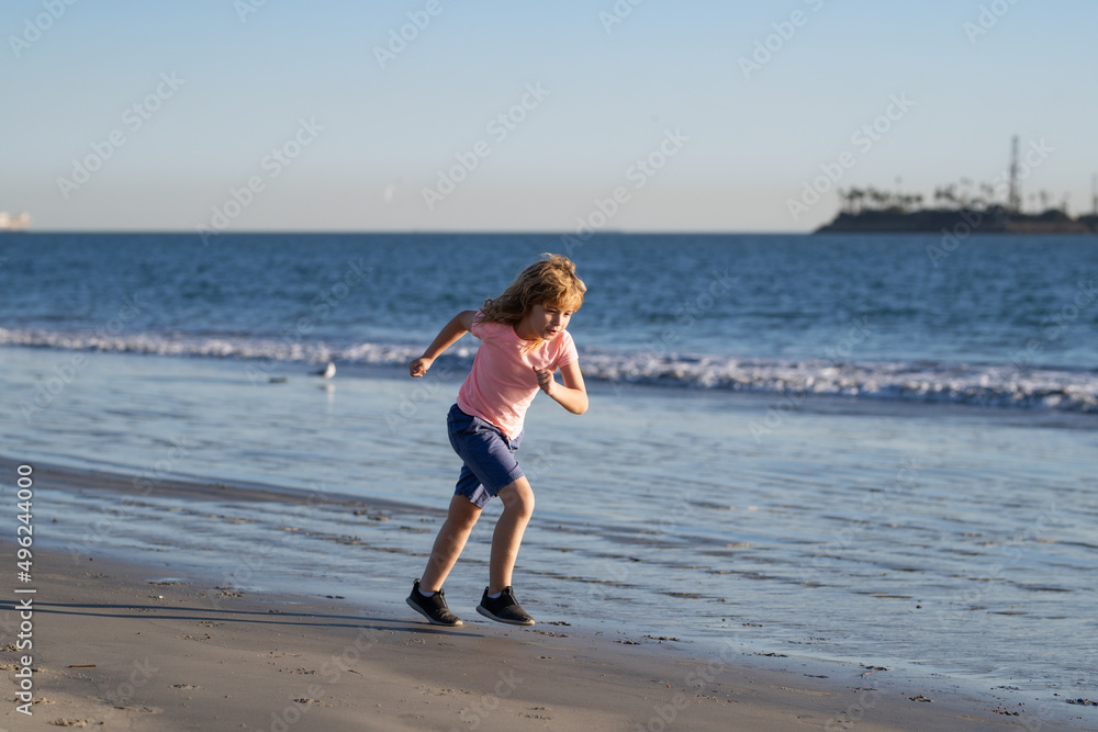 Kids playing on beach. Children play at sea on summer family vacation. Sand and water fun, sun protection. Little child running and jumping at ocean shore.