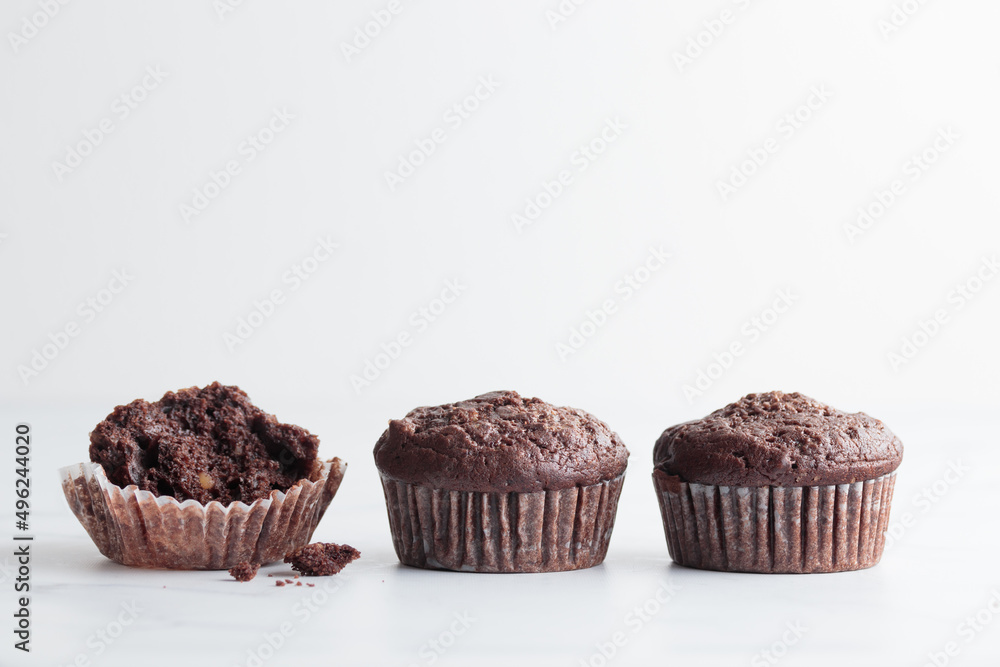 The row of chocolate muffins on a white table The row of chocolate muffins on a white table