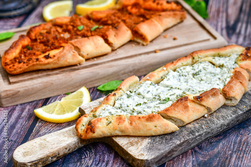  Traditional Turkish cuisine. Baked Pide dish with minced beef, tomatoes and cheese on wooden background. Turkish pizza pide