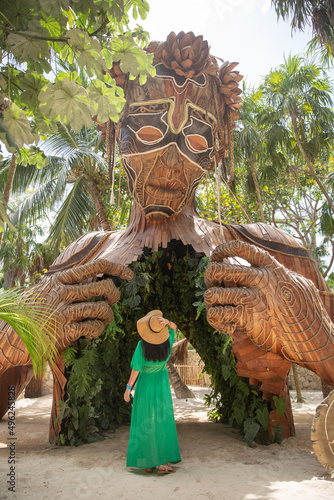 Giant sculpture by Daniel Popper called Ven a la Luz, or Coming into Light, in Tulum, Mexico, with a woman in green dress standing in front of it photo