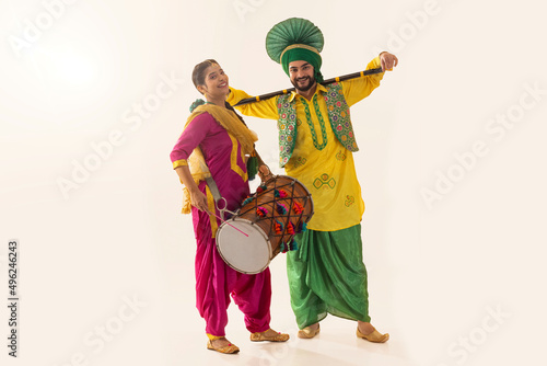 Sikh couple performing bhangra with drum and khunda during Baisakhi celebration photo