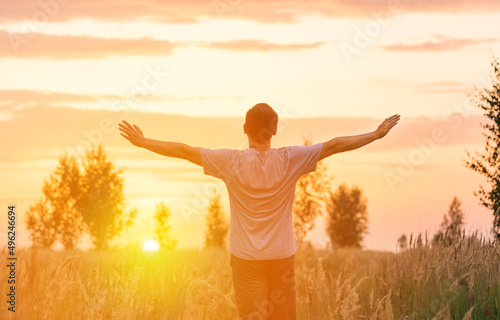 Freedom. A man looks at the setting sun with his arms outstretched