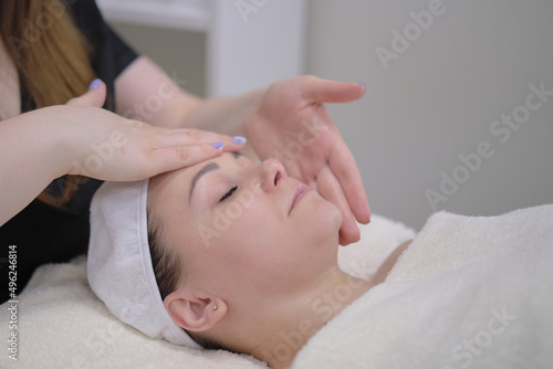 beauty therapist therapist doing cosmetic procedure. Calm patient woman undergoing the cosmetic facial massage procedures for rejuvenation skin face