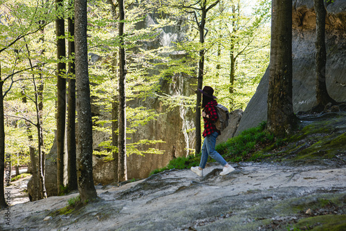 woman hiker with backpack walking by forest trail