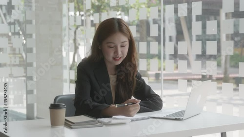 Young beautiful business woman is calculating and working on laptop then writing on note books.  photo