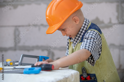 Child in helmet is construction worker. Foreman kid work in the hard hat making repairs. Childhood development. Little builder engineer. Improve your childhood. Kids building and repair.