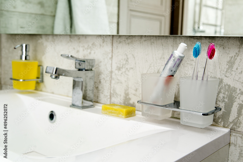 glass with two colored toothbrushes and soap in bright defocused bathroom with mirror. glass with two colored toothbrushes and soap in bright defocused bathroom with mirror.
