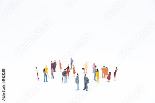 Group of miniature people meeting on white background.