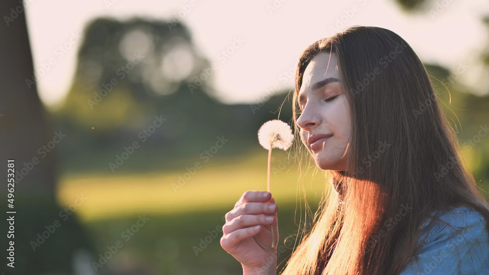 A young girl gently looks at the dandelion flower. A young girl gently looks at the dandelion flower.