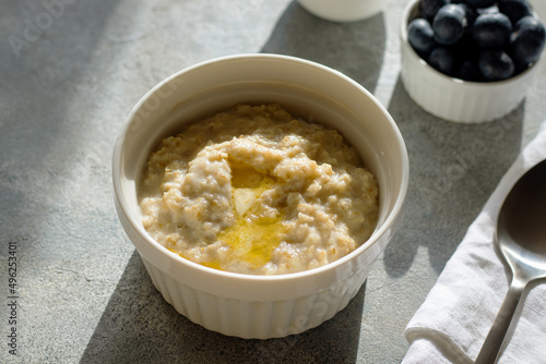 oatmeal porridge with blueberries and butter on grey background. Healthy eating, dieting, fitness food lifestyle concept photo