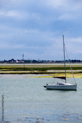 view from the beach of la patache on the preparing of a boat for sailing with the church of Ars-En-Re in the background on the isle of ile de Re in France