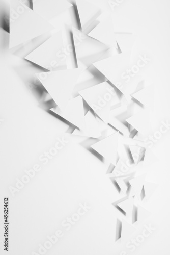 Abstract wave or white paper triangles flying in bright light with soft light shadows as flow, border, copy space, top view, vertical. Contemporary simple energy active airy abstract background. photo