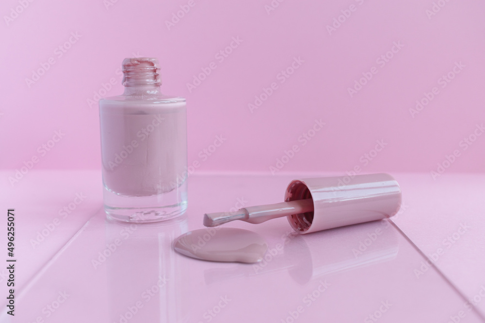 Pink brush with varnish on a pink background. Spilled nail polish. Mani Pedi. For nails. Cosmetology. Personal care. Manicure. Lacquer advertisement. Close-up photo. Pink brush with varnish on a pink background. Spilled nail polish. Mani Pedi. For nails. Cosmetology. Personal care. Manicure. Lacquer advertisement. Close-up photo.