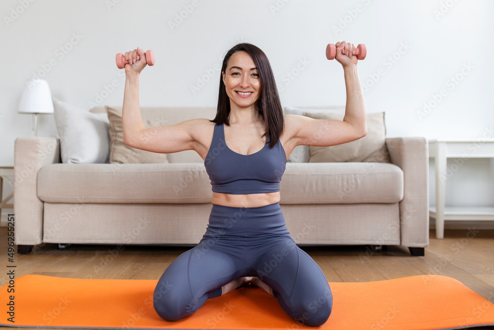 Asian woman exercise with dumbbells at home. Happy female doing arm workout using dumbbells Asian woman exercise with dumbbells at home. Happy female doing arm workout using dumbbells
