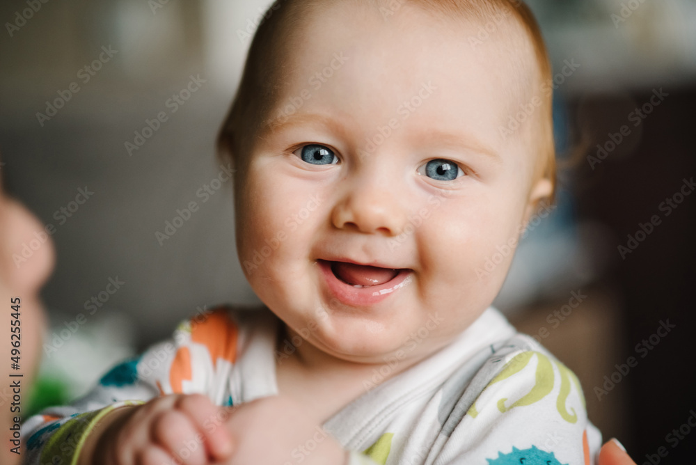 Baby portrait. Closeup face with bright blue eyes boy. Ophthalmology, curiosity, happiness, exploring the world, joy, childhood, psychology. First teeth. Looking at the camera.