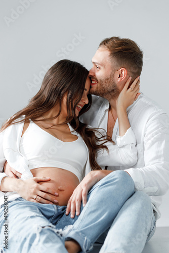 Beautiful couple of a man and pregnant woman smiling happily hugging and kissing together