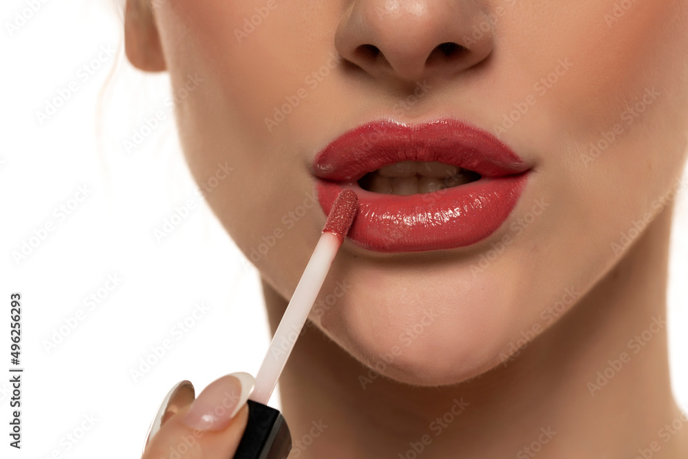 young beautiful woman apply a lip gloss on her lips on white background young beautiful woman apply a lip gloss on her lips on white background