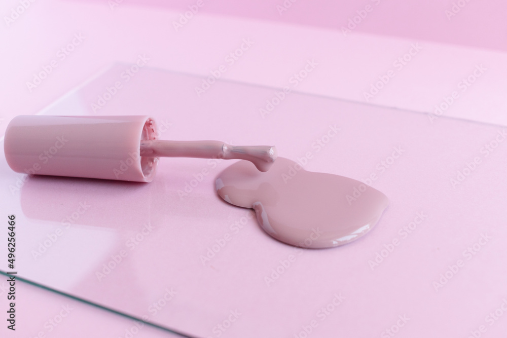 Pink brush with varnish on a pink background. Spilled nail polish. Mani Pedi. For nails. Cosmetology. Personal care. Manicure. Lacquer advertisement. Close-up photo. Pink brush with varnish on a pink background. Spilled nail polish. Mani Pedi. For nails. Cosmetology. Personal care. Manicure. Lacquer advertisement. Close-up photo.