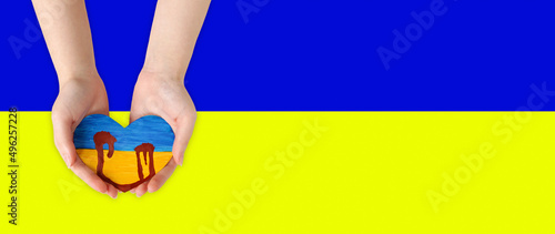 a children's drawing on paper, a bleeding heart in his hands. Bleeding of the heart in the hands. Flag of Ukraine, symbol of the war in Ukraine, drawing on paper