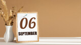 september 6. 6th day of month, calendar date.White vase with dead wood next to cork board with numbers. White-beige background with striped shadow. Concept of day of year, time planner, autumn month