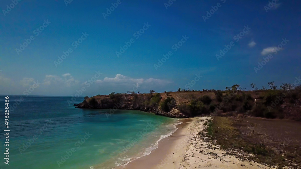 A panoramic view on an idyllic Pink Beach on Lombok, Indonesia. Sea is calm, shining with many shades of blue. Beauty in the nature. Unspoiled, hidden gem. Perfect place for peaceful, relaxed holidays