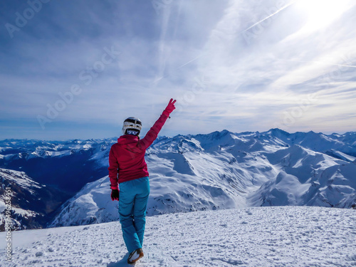 Snowboarding girl standing on the top of a mountain in Moelltaler Gletscher, Austria, enjoying the view. Lots of snow in the mountains. Endless Alps chain. Winter wonderland. Calmness and happiness. photo