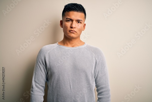 Canvastavla Young handsome latin man wearing casual sweater standing over isolated white background Relaxed with serious expression on face