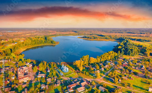 Incredible summer view from flying drone of Kazansʹkoyi Ikony Presvyatoyi Bohorodytsi church, Volyn region, Ukraine, Europe. Captivating morning scene of Pishchans'ke lake. photo