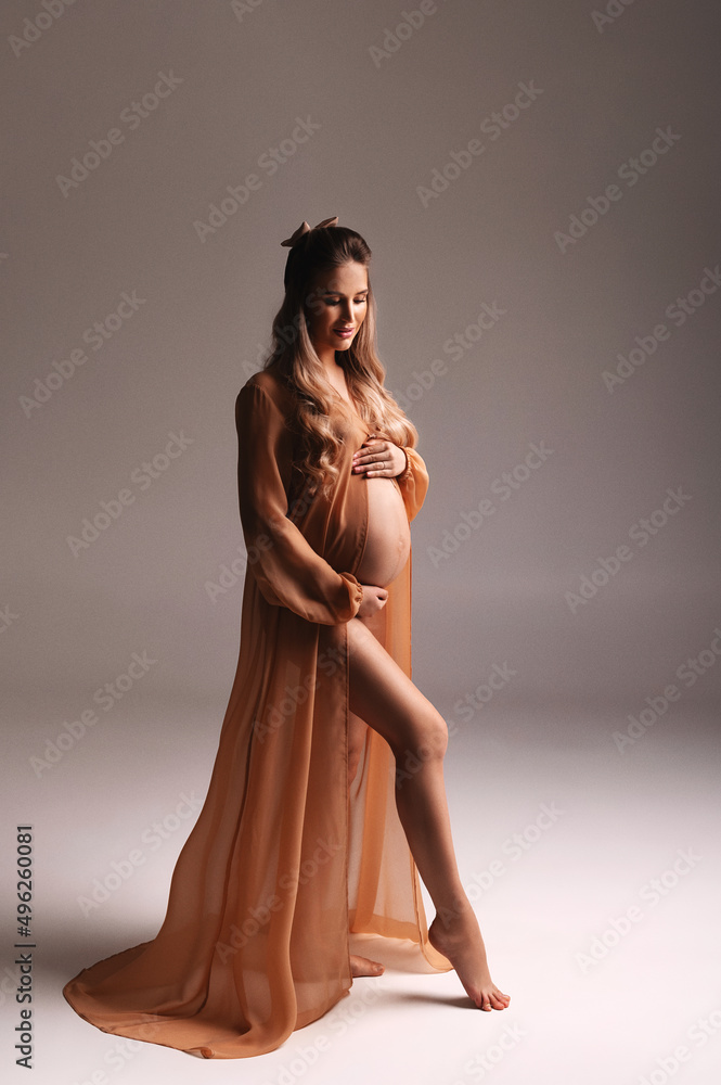 the pregnant woman poses in the studio. beautiful pregnant blonde woman. the pregnant woman poses in the studio. beautiful pregnant blonde woman.