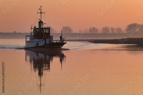 Ferry sailing across the Ems river from Ditzum to Petkum at sunset, East Frisia, Lower Saxony, Germany photo