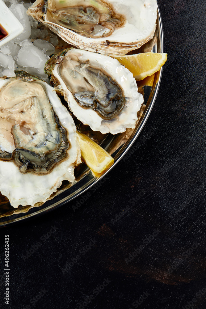 Oysters with lemon served on black round platter. Luxury delicatessen seafood. Oysters with lemon served on black round platter. Luxury delicatessen seafood.