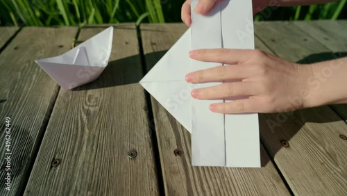 Crafting origami figure with white paper. Male hands, folding and bending colourful paper sheet. photo