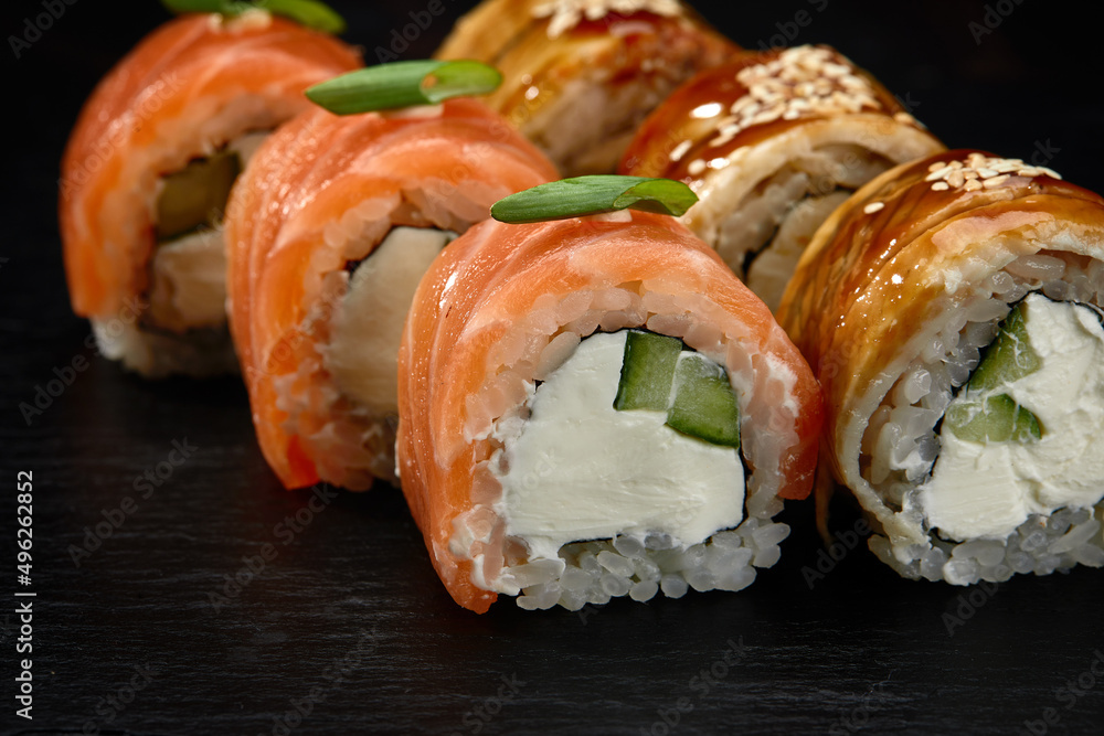 Traditional Japanese rolls with salmon and smoked eel in set on black background. Traditional Japanese rolls with salmon and smoked eel in set on black background.