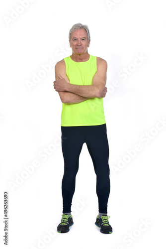 front view of a man in sportswear tights and fluorescent yellow sleeveless looking at camera arms crossed on white background