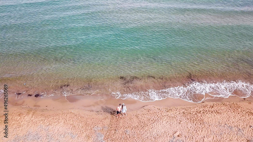 A couple standing at Lara Beach in Cyprus. Hidden gem, not spoiled by tourists. Solitude and calm feelings, waves gently spreading on the beach. turquoise color of the water. Sand has pink shade. photo