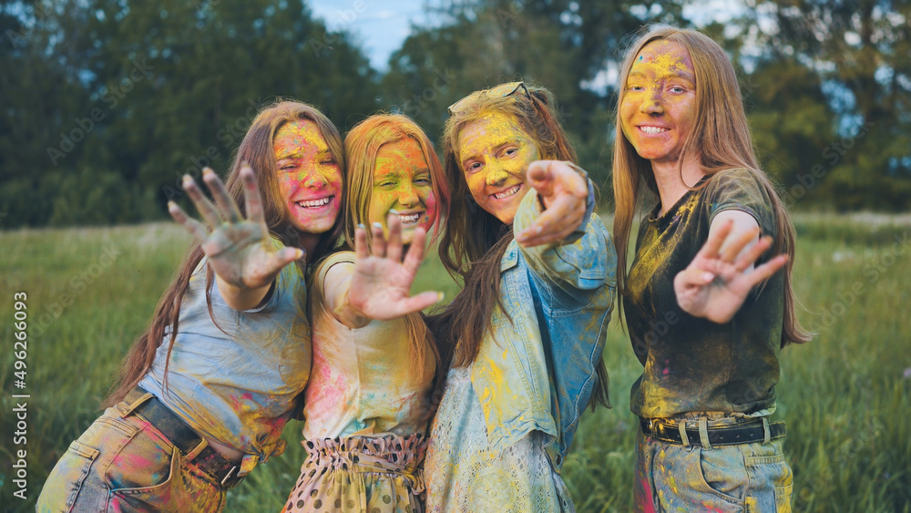 Fototapeta premium Cheerful girls posing smeared in multi-colored powder.
