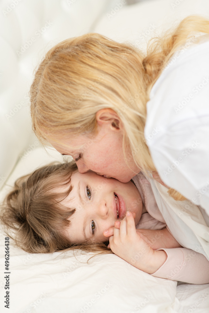 Mom kissing a girl with down syndrome in the bedroom on the bed while going to bed. Mom kissing a girl with down syndrome in the bedroom on the bed while going to bed.