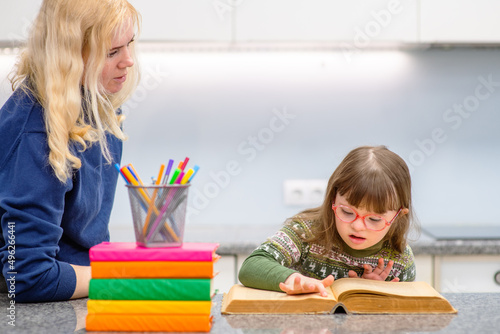 Mom helps a girl with down syndrome to do her homework for school. Family education for children with disabilities