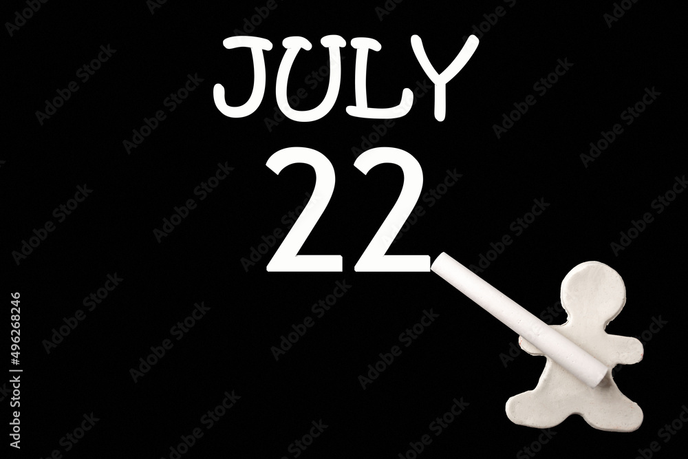 A small white plasticine man writing the date 22July on a black board. Business concept. Education concept. A small white plasticine man writing the date 22July on a black board. Business concept. Education concept.