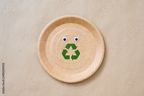 Fototapeta Naklejka Na Ścianę i Meble -  Biodegradable paper plate with eyes and recycling sign. The concept of a call for environmental protection.