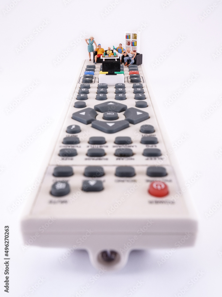 Family spending time together channel surfing and watching a television, conceptual photography. Miniature figurines on the TV remote, watching football match or movie. Family spending time together channel surfing and watching a television, conceptual photography. Miniature figurines on the TV remote, watching football match or movie.