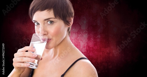 Portrait of fit woman drinking water against copy space on red background