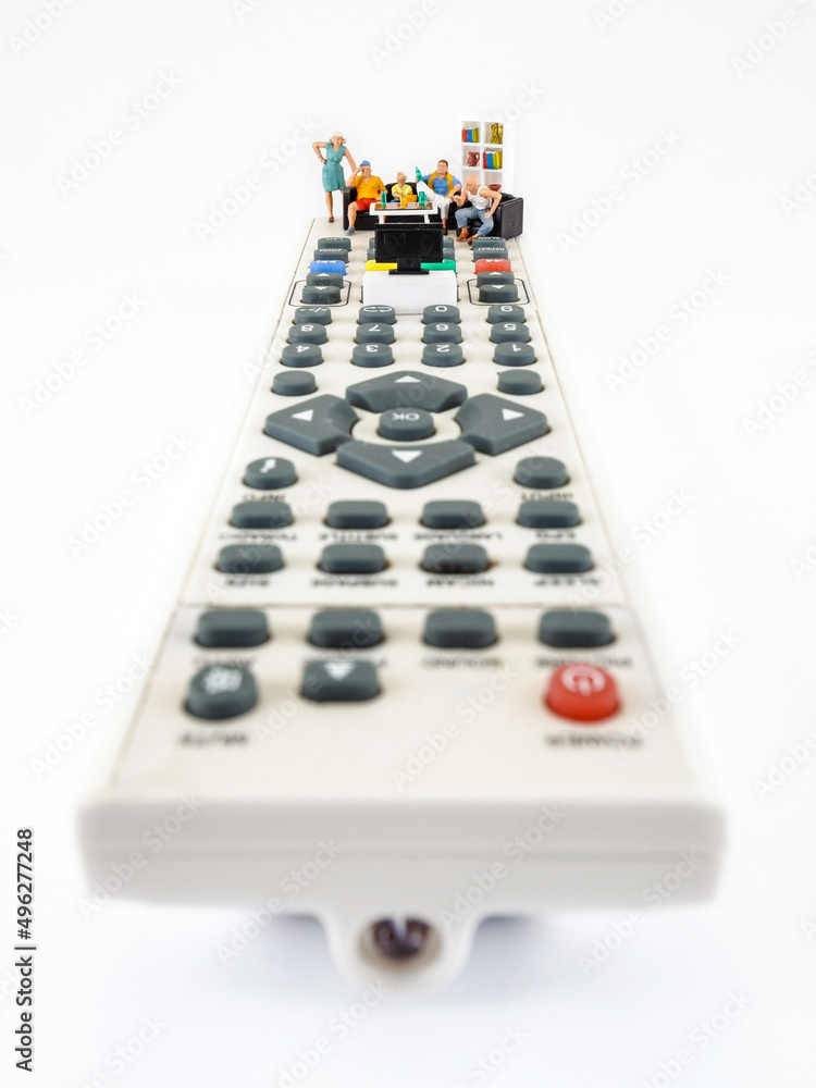 Family spending time together channel surfing and watching a television, conceptual photography. Miniature figurines on the TV remote, watching football match or movie. Family spending time together channel surfing and watching a television, conceptual photography. Miniature figurines on the TV remote, watching football match or movie.