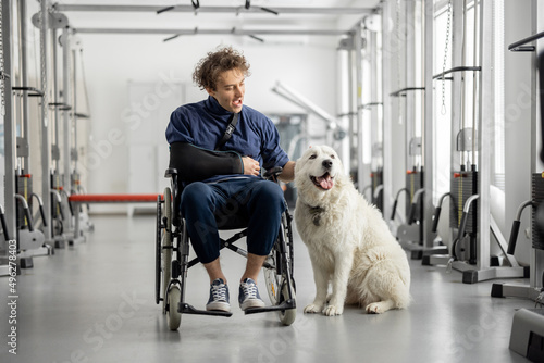 Photography Young guy with disabilities sits in a wheelchair with his friendly dog at rehabilitation center