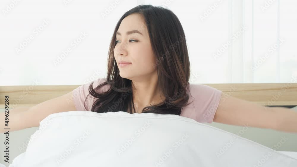 Asian beautiful woman waking up in the morning at home. Young girl stretches and gets up from bed in bedroom at home. Concept of lifestyle, vacation and healthy. Asian beautiful woman waking up in the morning at home. Young girl stretches and gets up from bed in bedroom at home. Concept of lifestyle, vacation and healthy.
