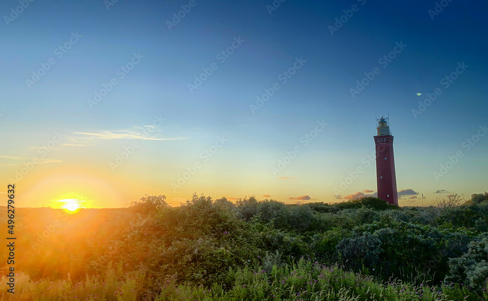 Lighthouse standing on the Dutch coast with a dramatic. and colorful sunset or sunrise sky behind it. High quality photo