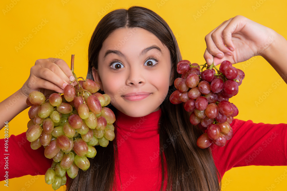 amazed positive teen girl hold bunch of grapes on yellow background amazed positive teen girl hold bunch of grapes on yellow background
