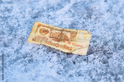 Old paper banknote of the Russian ruble of 1961 on the snow. A symbol of the economic conflict of world powers and the frozen exchange rate of the national currency.